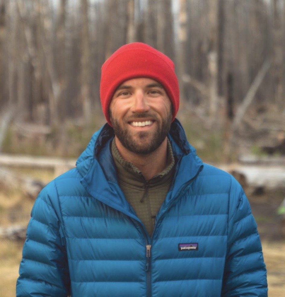Brandon Whitley wearing a red beanie and blue jacket in the forest near Mt. Adams